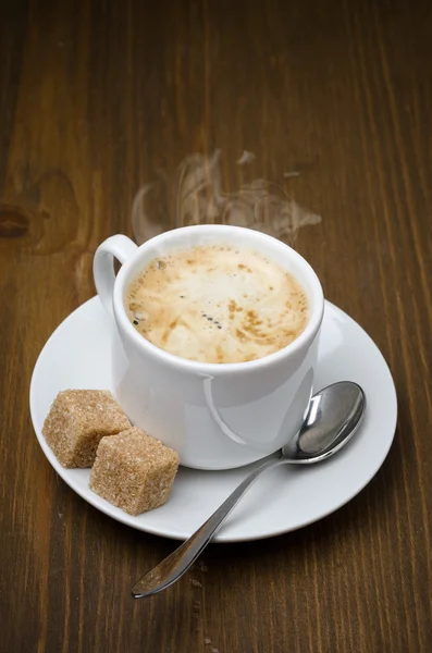 Kopje zwarte koffie met schuim en rietsuiker kubussen — Stockfoto