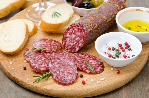 Italian salami, bread and spices on a cutting board — Stock Photo, Image
