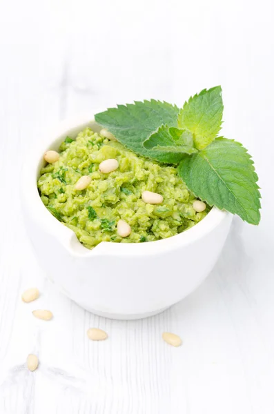 Primo piano di pesto di piselli verdi con menta su fondo bianco — Foto Stock