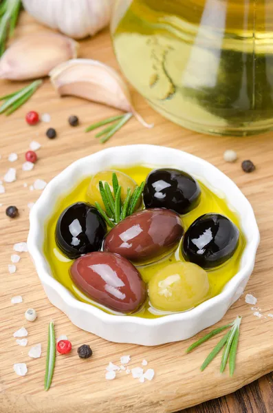 Tres variedades de aceitunas en un bol con aceite de oliva y especias — Foto de Stock