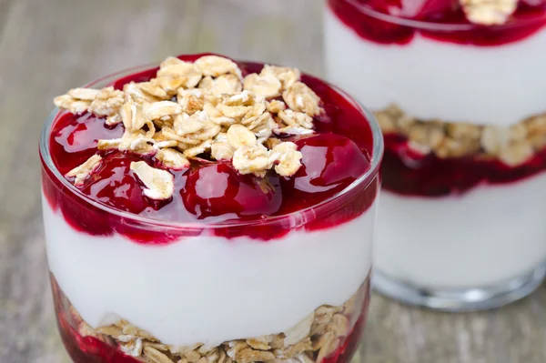 Два стакана с десертом из йогурта, мюсли, вишни — стоковое фото