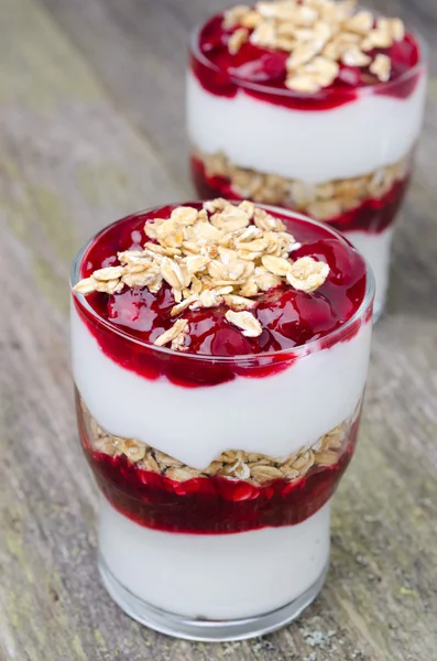 Dos vasos con postre en capas con yogur, granola y cereza —  Fotos de Stock