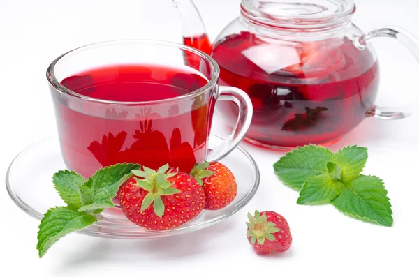Чайник и чашка красного чая с клубникой и мятой на белом — стоковое фото