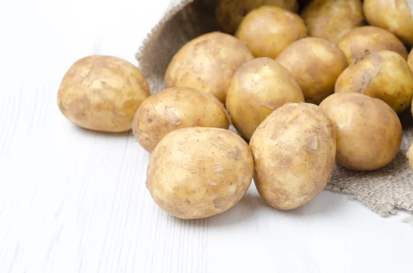 Nieuwe aardappelen in een zak op een witte achtergrond, selectieve aandacht — Stockfoto