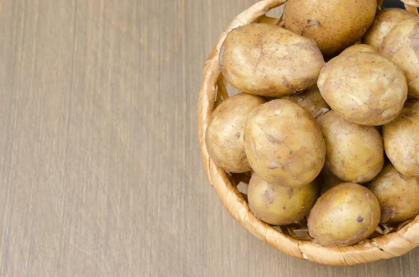 Draufsicht auf neue Kartoffeln in einem Korb auf grauem Holzgrund — Stockfoto