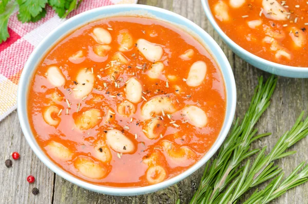 Two bowls of tomato soup with pasta, white beans and rosemary — Stock Image Two bowls of tomato soup with pasta, white beans and rosemary Royalty Free Stock Images