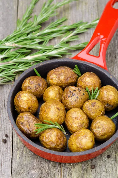 Gebakken nieuwe aardappelen met rozemarijn in koekenpan verticale — Stockfoto