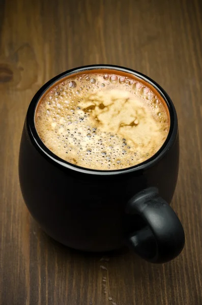 Ahşap bir masa, üstten görünüm üzerinde köpük koyu bir kahve bir fincan — Stok fotoğraf
