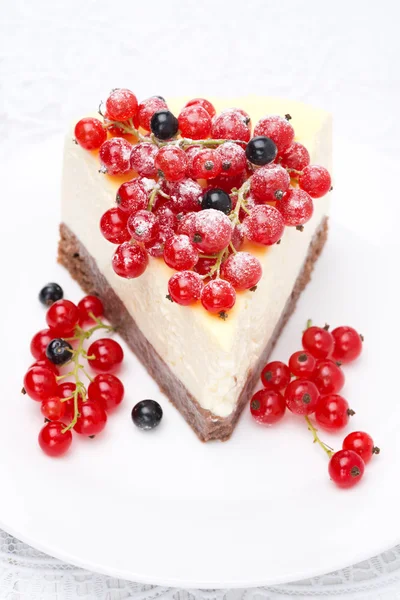 Piece of cheesecake, decorated with red and black currants — Stock Photo, Image