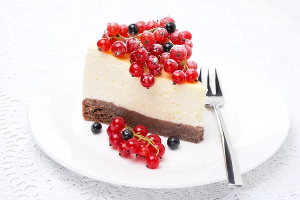 Piece of cheesecake, decorated with red and black currants — Stock Photo, Image