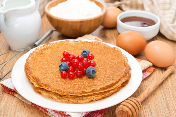 Crepes with fresh berries and ingredients for baking on a wooden — Stock Photo, Image