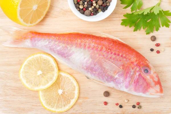Fresh surmullet, lemon and spices on a wooden cutting board — Stock Photo, Image