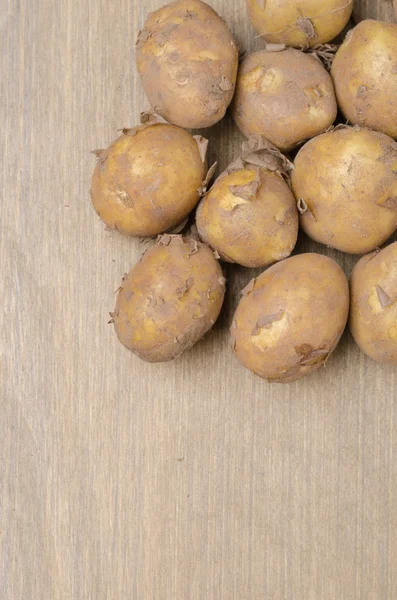 Potatoes on a wooden background, vertical, top view — Stockfoto