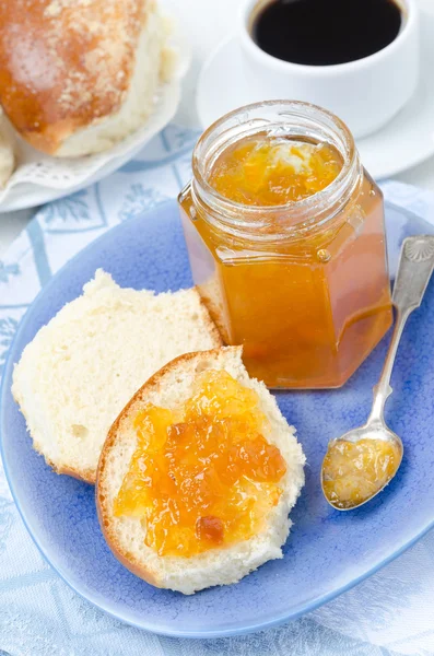 Sweet bun with apricot jam on plate and coffee for breakfast — Stock Photo, Image