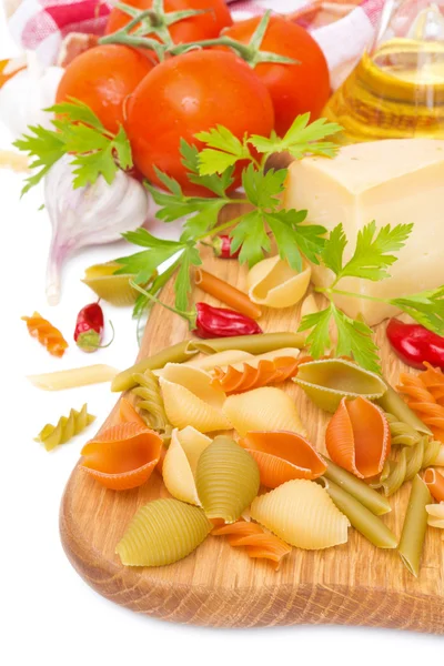 Colored pasta, cheese, spices, olive oil and tomatoes — Stock Photo, Image