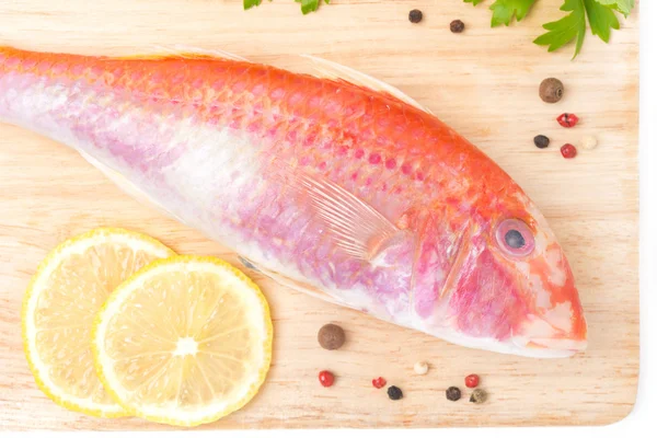 Fresh surmullet, lemon and pepper on a wooden board, top view — Stock Photo, Image