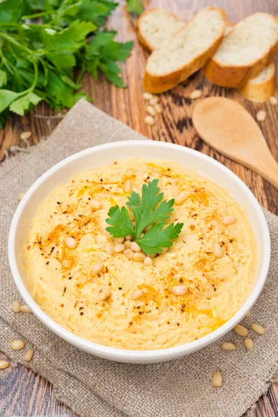 Hummus mit Pinienkernen in einer Schüssel, senkrecht, Ansicht von oben — Stockfoto