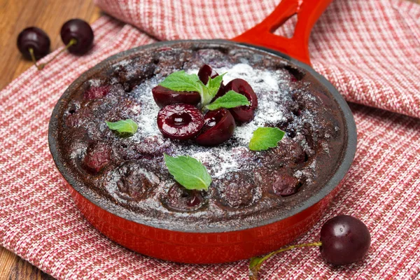 Chocolate clafoutis with cherries in a frying pan, close-up — Stock Photo, Image