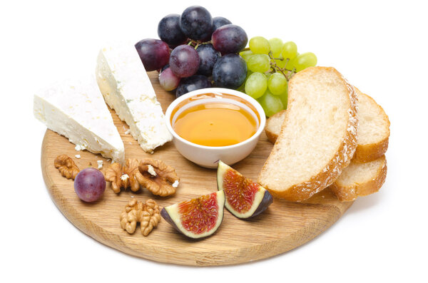 Cheese, bread, figs, grapes, honey and nuts on a wooden board