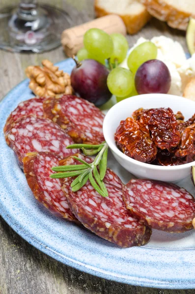 Snack su un piatto - salsiccia, pomodori asciugati dal sole, noci, frutto — Foto Stock