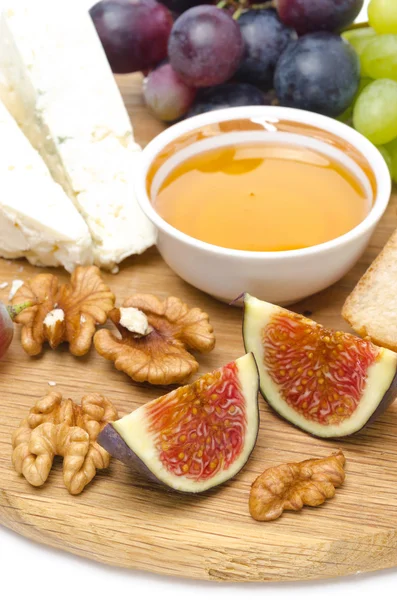 Queso, pan, higos, uvas, miel y nueces en una tabla de madera —  Fotos de Stock