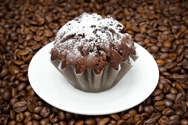 Magdalena de chocolate sobre un fondo de granos de café —  Fotos de Stock