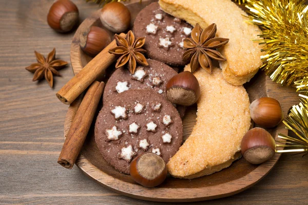 Рождественское печенье, специи и орехи на деревянной тарелке — стоковое фото