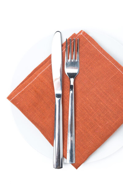 Serving - fork, knife and napkin on a plate, isolated, top view