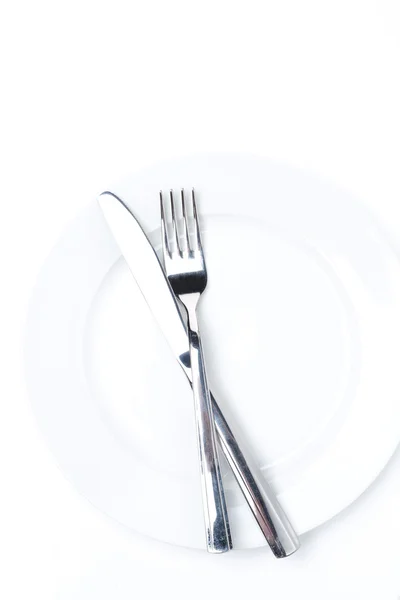 Tenedor y cuchillo en un plato blanco, aislado — Foto de Stock