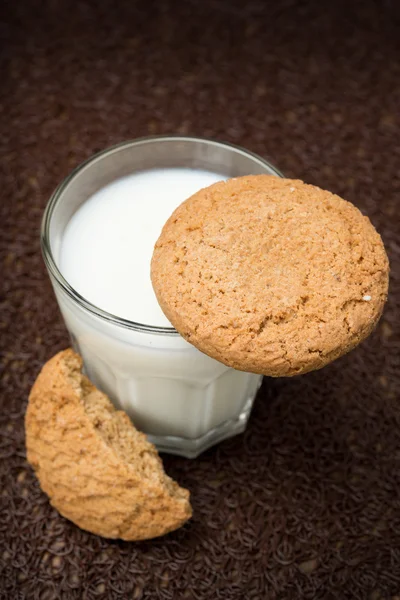 Vetro di latte e biscotti di avena su uno sfondo scuro — Foto Stock