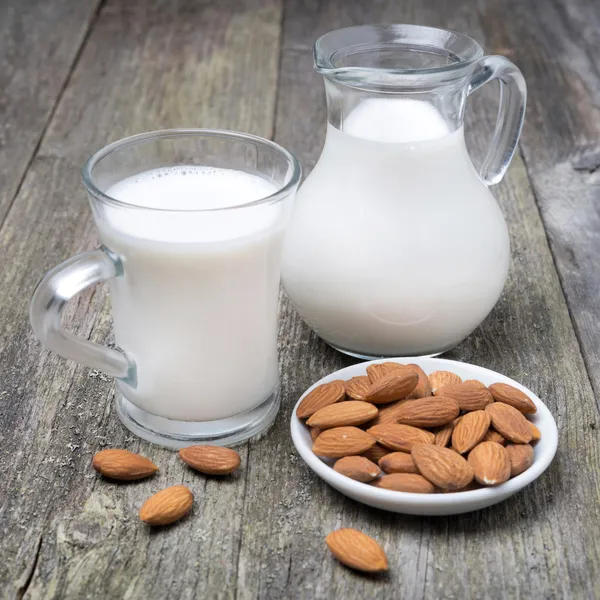 Jarra y taza de vidrio con leche de almendras —  Fotos de Stock