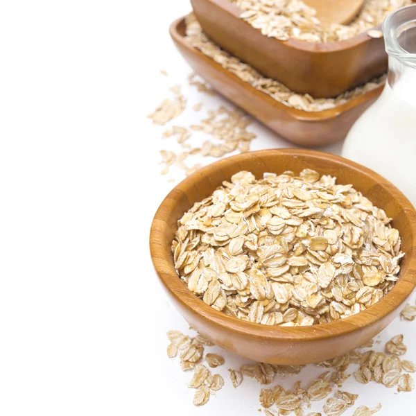 Oat flakes in wooden bowl and a jug of milk, isolated — Stock Photo, Image