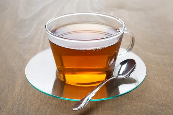 Taza transparente de té negro sobre fondo de madera — Foto de Stock