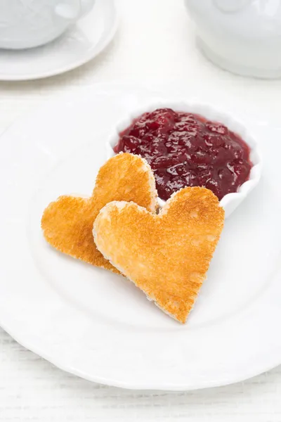 Two toast bread in the shape of hearts and berry jam in a bowl — Stock Photo, Image