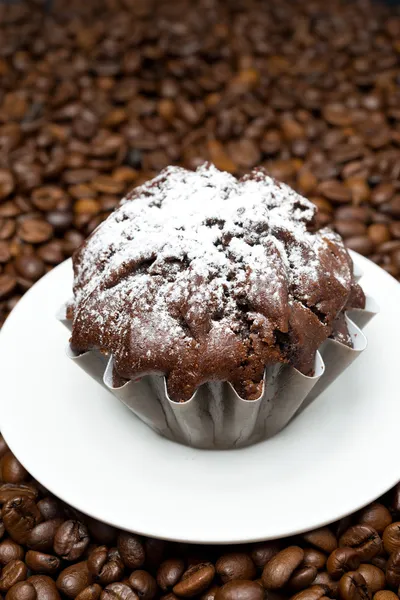 Шоколадный кекс на фоне кофейных зерен, крупным планом — стоковое фото