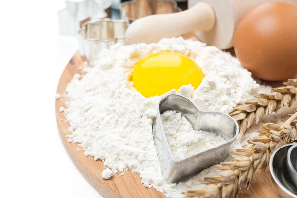 Flour, eggs, rolling pin and baking forms on wooden board — Stock Photo, Image