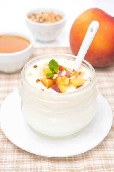 Домашний йогурт с медом, персиками и орехами в стеклянной банке — стоковое фото
