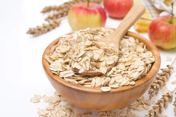 Fiocchi d'avena in una ciotola di legno e mele sullo sfondo — Foto Stock