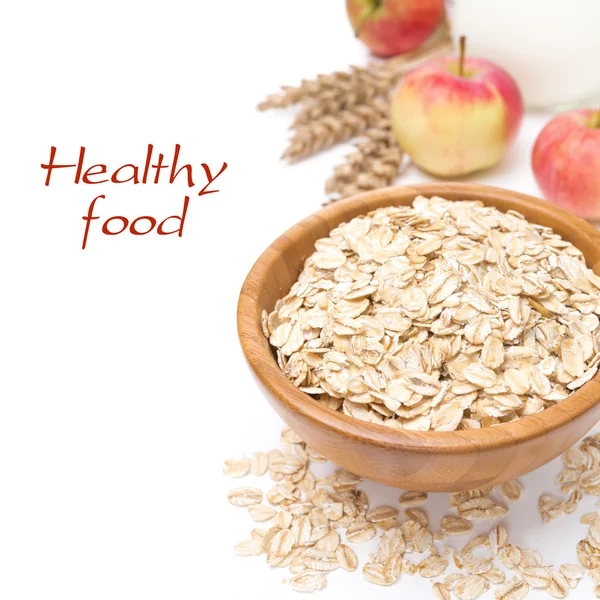 Oat flakes in wooden bowl and apples in the background, isolated — Stock Photo, Image
