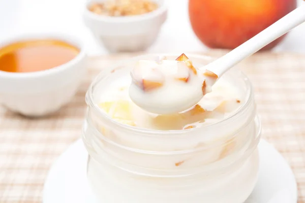 Yogur con miel, melocotones frescos, nueces en una cuchara —  Fotos de Stock