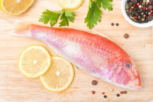 Fresh surmullet, lemon and spices on a wooden board — Stock Photo, Image