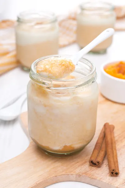 Frascos de yogur con puré de calabaza especiado en una tabla de madera —  Fotos de Stock