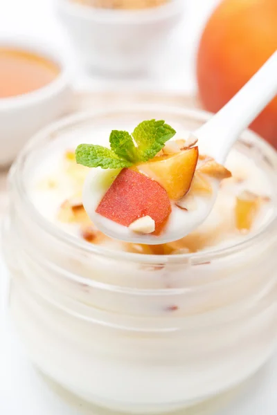 Yoghurt with honey, peaches, nuts in a spoon close-up — Stock Photo, Image
