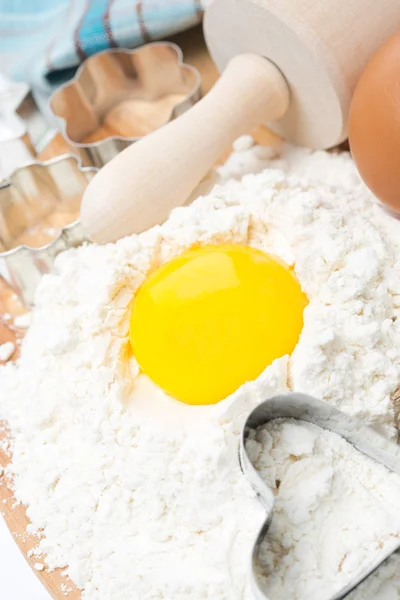 Baking ingredients - flour, egg and baking forms on wooden board — Stock Photo, Image