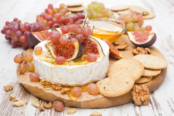 Закуски - камамбер, мед, орехи, фрукты и крекеры — стоковое фото