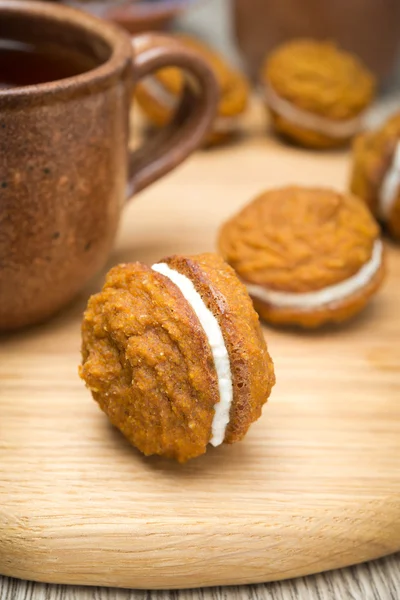 Pumpkin cookies with cream filling and cup of tea — Stock Photo, Image