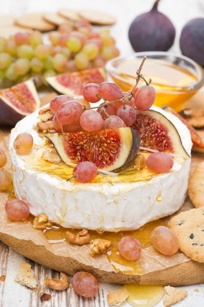 Камамбер с виноградом, инжиром, медом и грецкими орехами на деревянной доске — стоковое фото