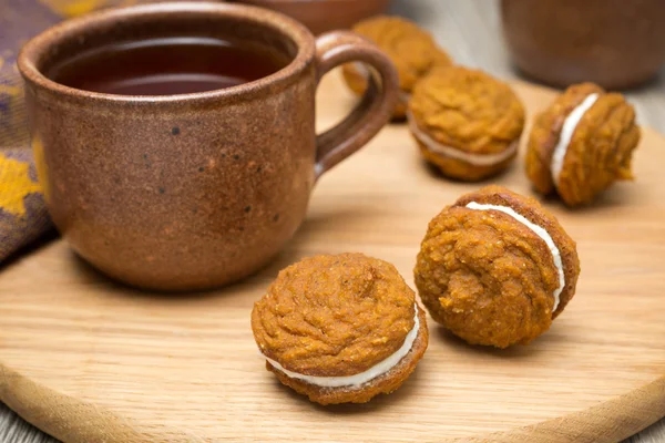 Biscoitos de abóbora com recheio de creme e uma xícara de chá — Fotografia de Stock