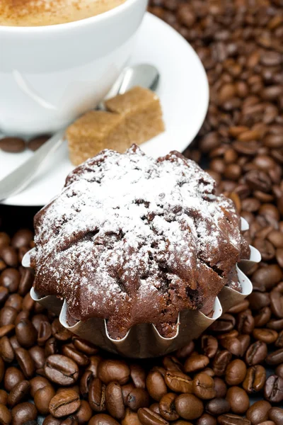 Schokoladenmuffin und Cappuccino mit braunem Zucker auf Kaffeebohnen — Stockfoto