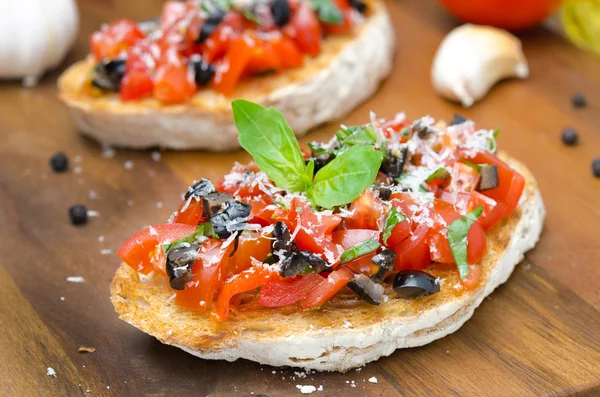 Italian bruschetta with tomato, olives, basil and cheese — Stock Photo, Image